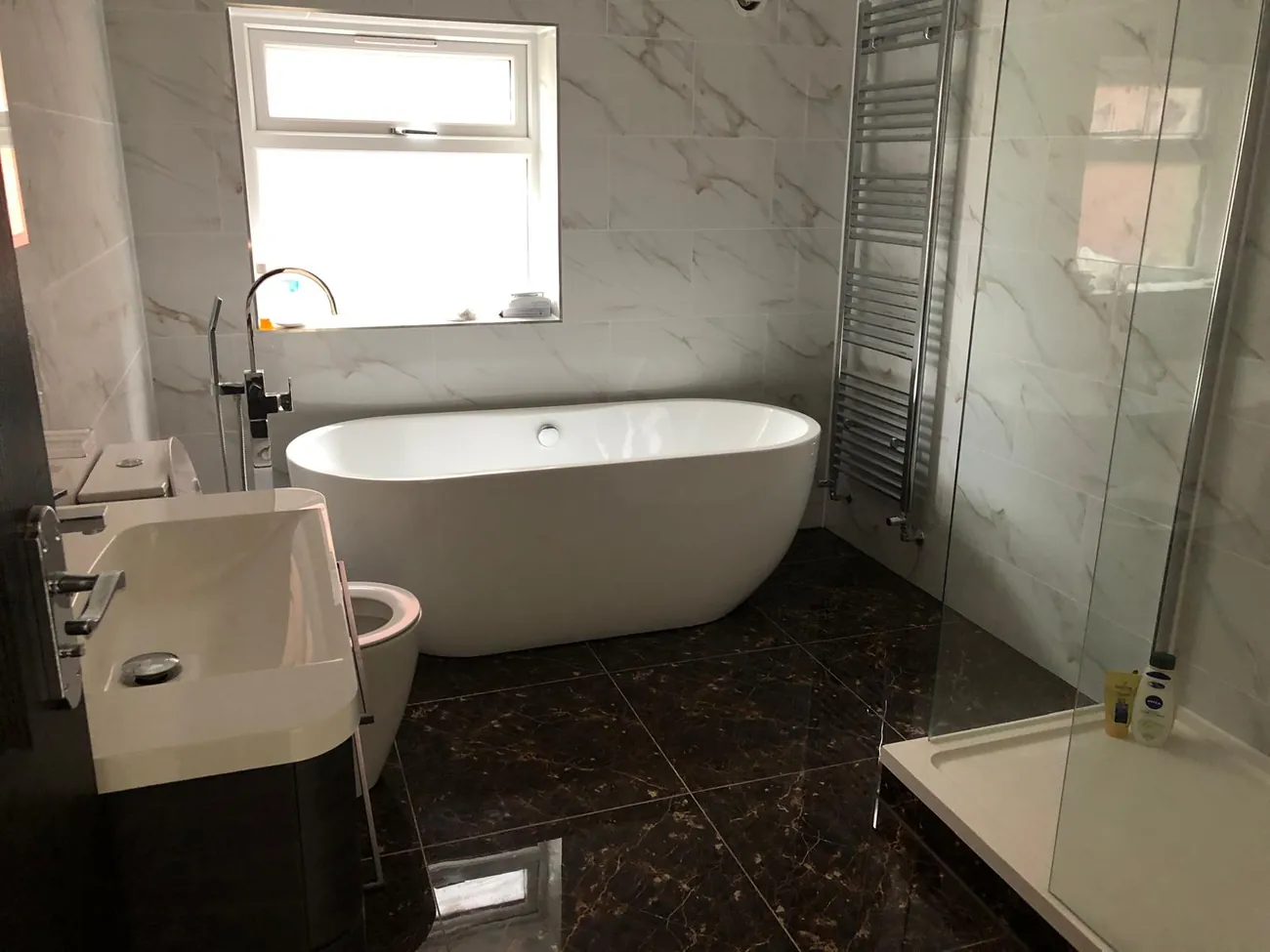 Finished bathroom with marble-effect tiling, a freestanding bath and walk-in shower