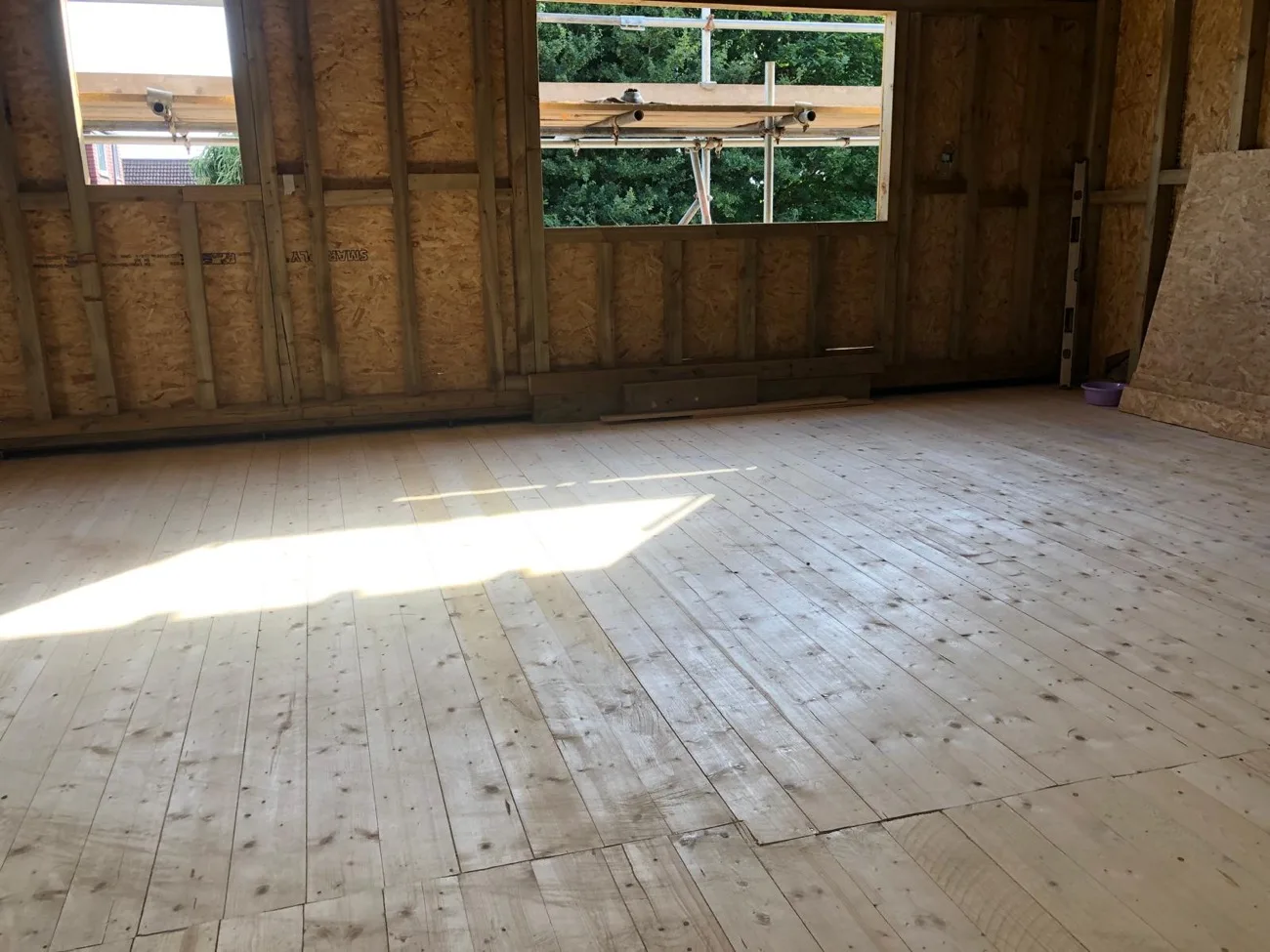 Loft conversion room with new floorboards and gable windows