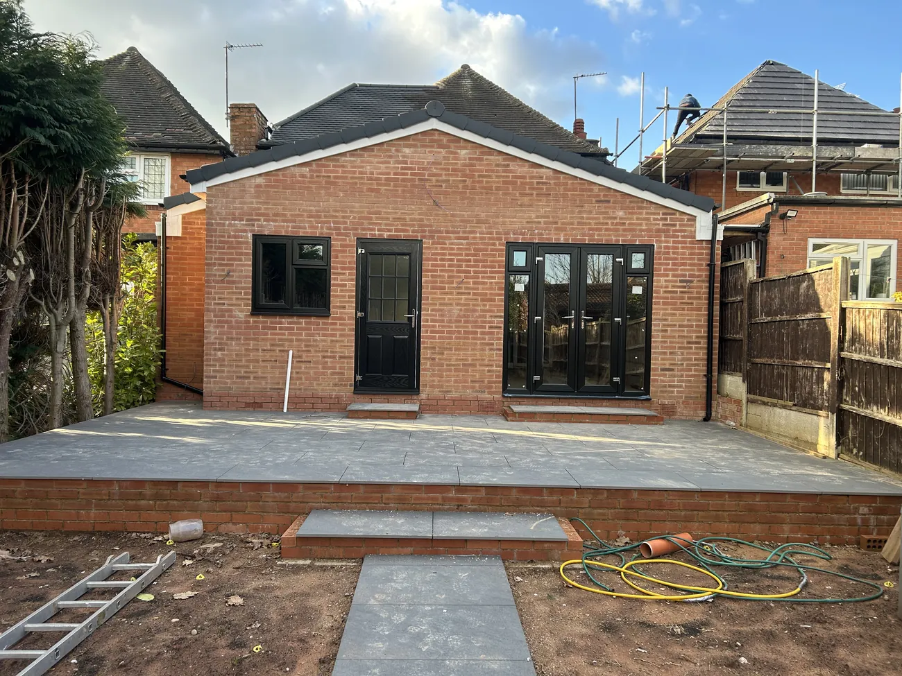 Completed single-storey rear extension with black bifold doors and a new patio